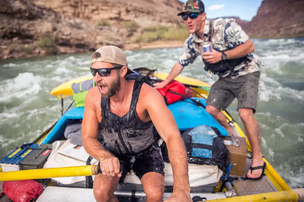 A rower getting soaked with someone behind him on the Grand Canyon